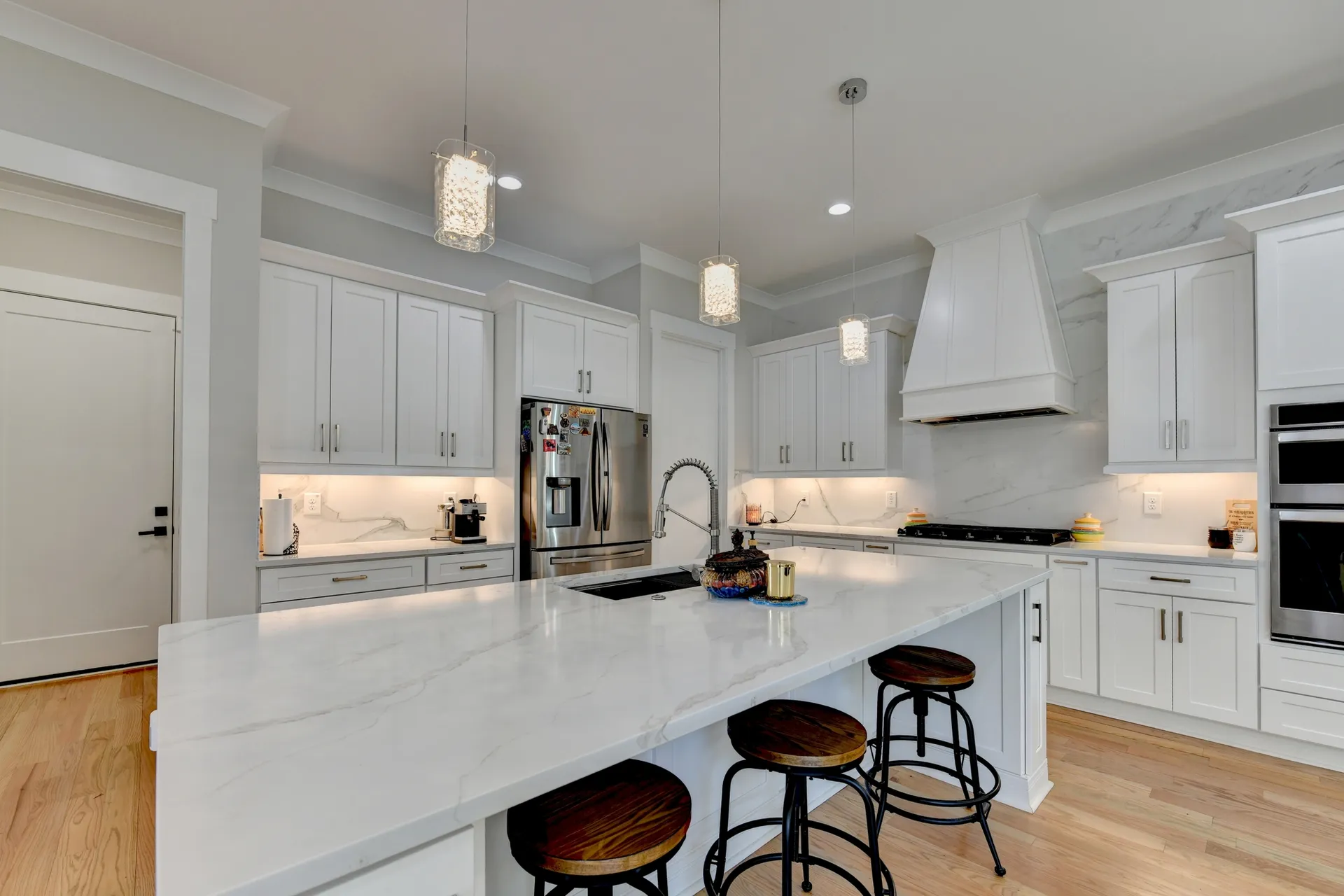 White kitchen with oversized quartz island and stainless steel appliances